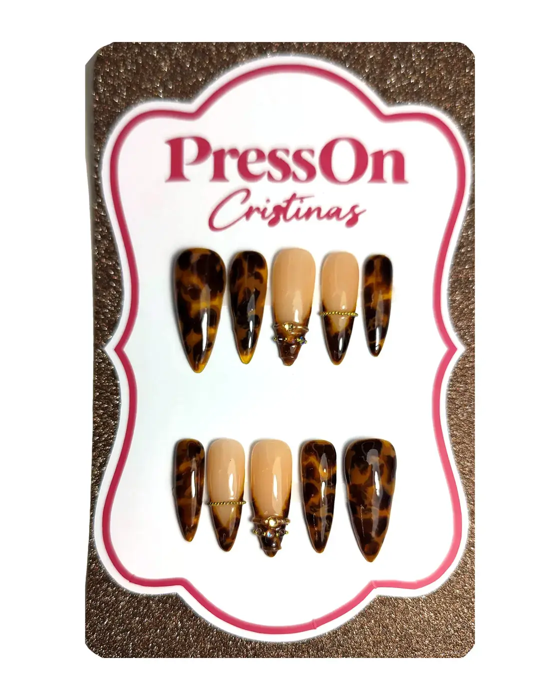 Uñas postizas stiletto con estampado carey y acento nude con charm dorado, sobre cartulina PressOn Cristina's, vista frontal
