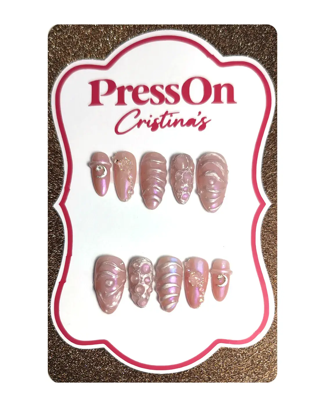 Uñas postizas almendra con relieve 3D, efecto cromado unicornio y charms de luna y rosa, sobre cartulina PressOn Cristina's, vista frontal